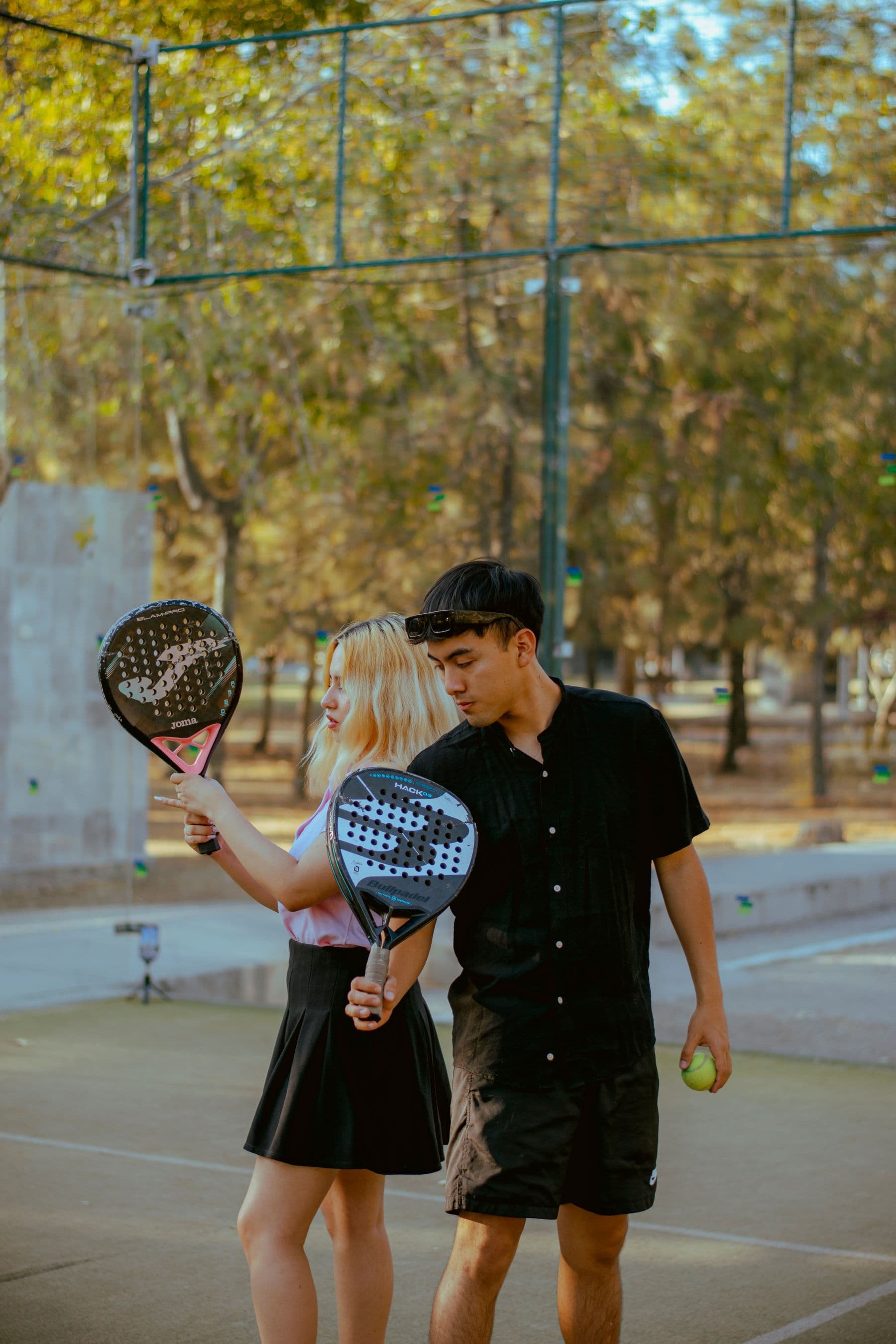 Dois jogadores com raquetes de padel num campo ao ar livre